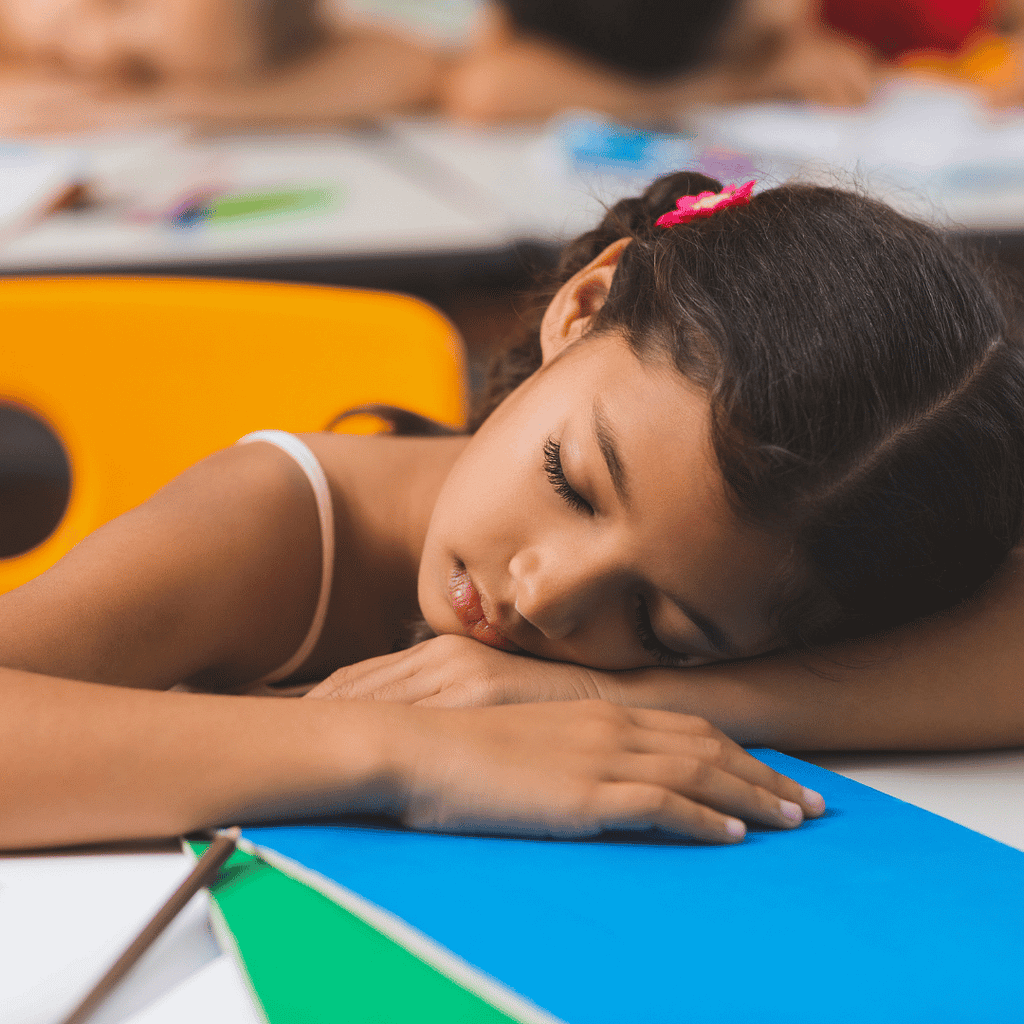child sleeping at desk at school