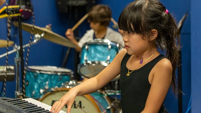 Backbeat-Music-Academy-portland-OR-a-boy-playing-drums-and-a-girl-playing-piano-together-during-music-lessons-at-backbeat-music-academy