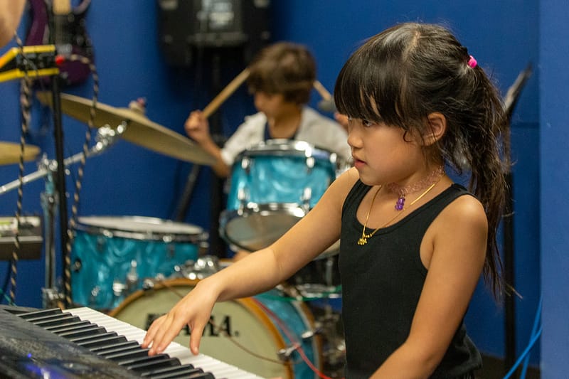 Backbeat-Music-Academy-portland-OR-a-boy-playing-drums-and-a-girl-playing-piano-together-during-music-lessons-at-backbeat-music-academy